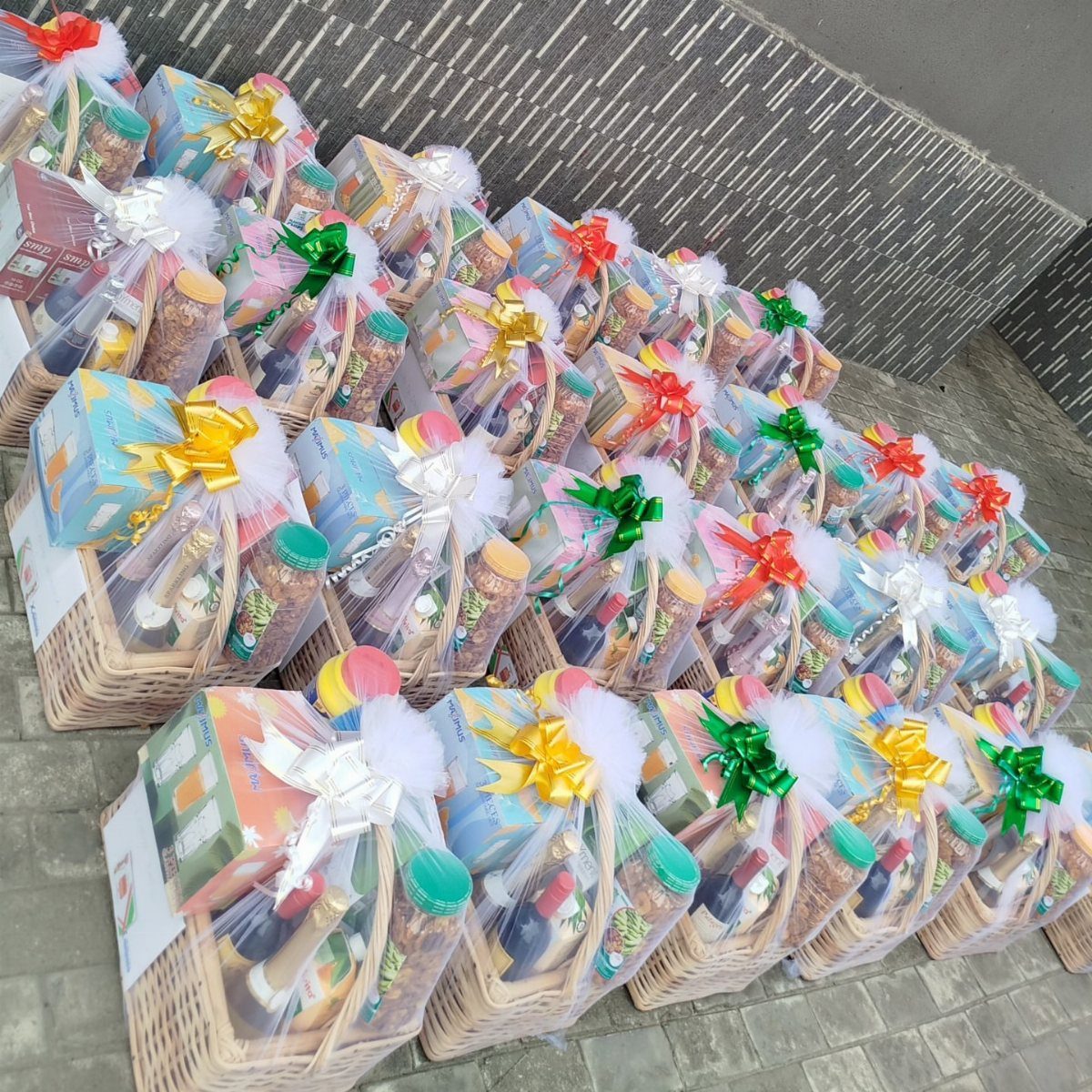 Wicker gift baskets wrapped in cellophane with colorful bows containing gourmet food treats.