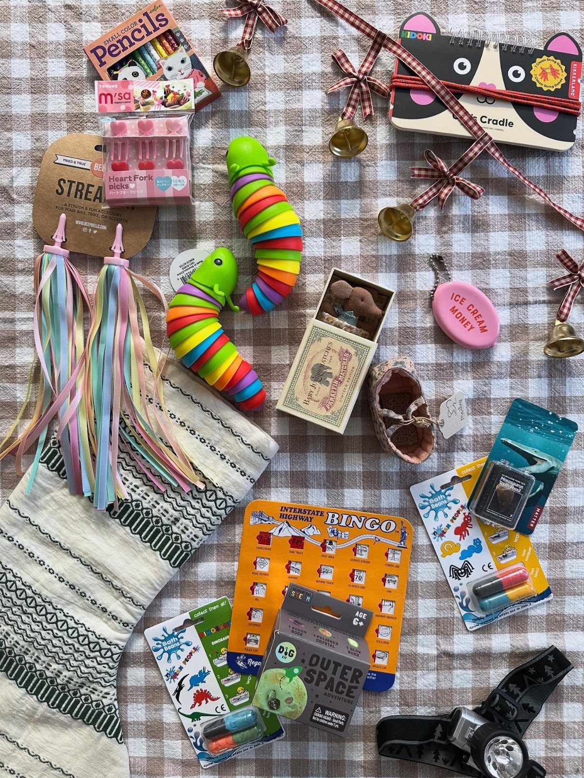 Assorted small novelty gifts and a stocking arranged on a checkered fabric background.