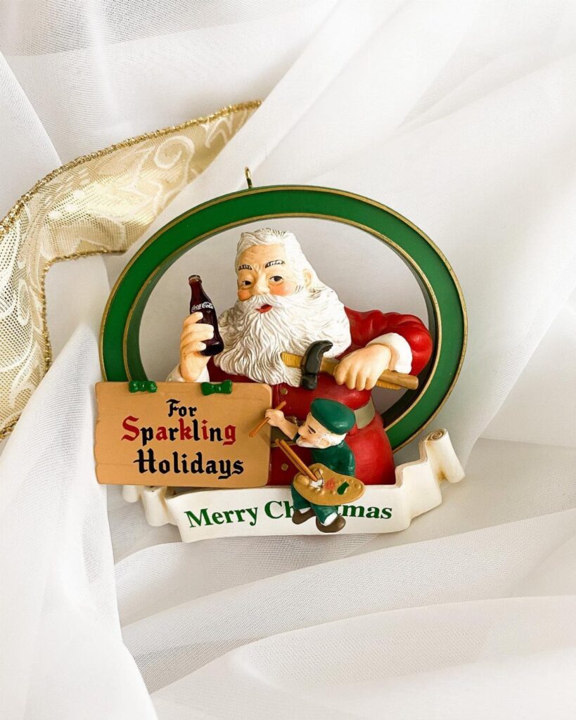 Santa Claus ornament holding a Coca-Cola bottle with a small elf playing banjo.