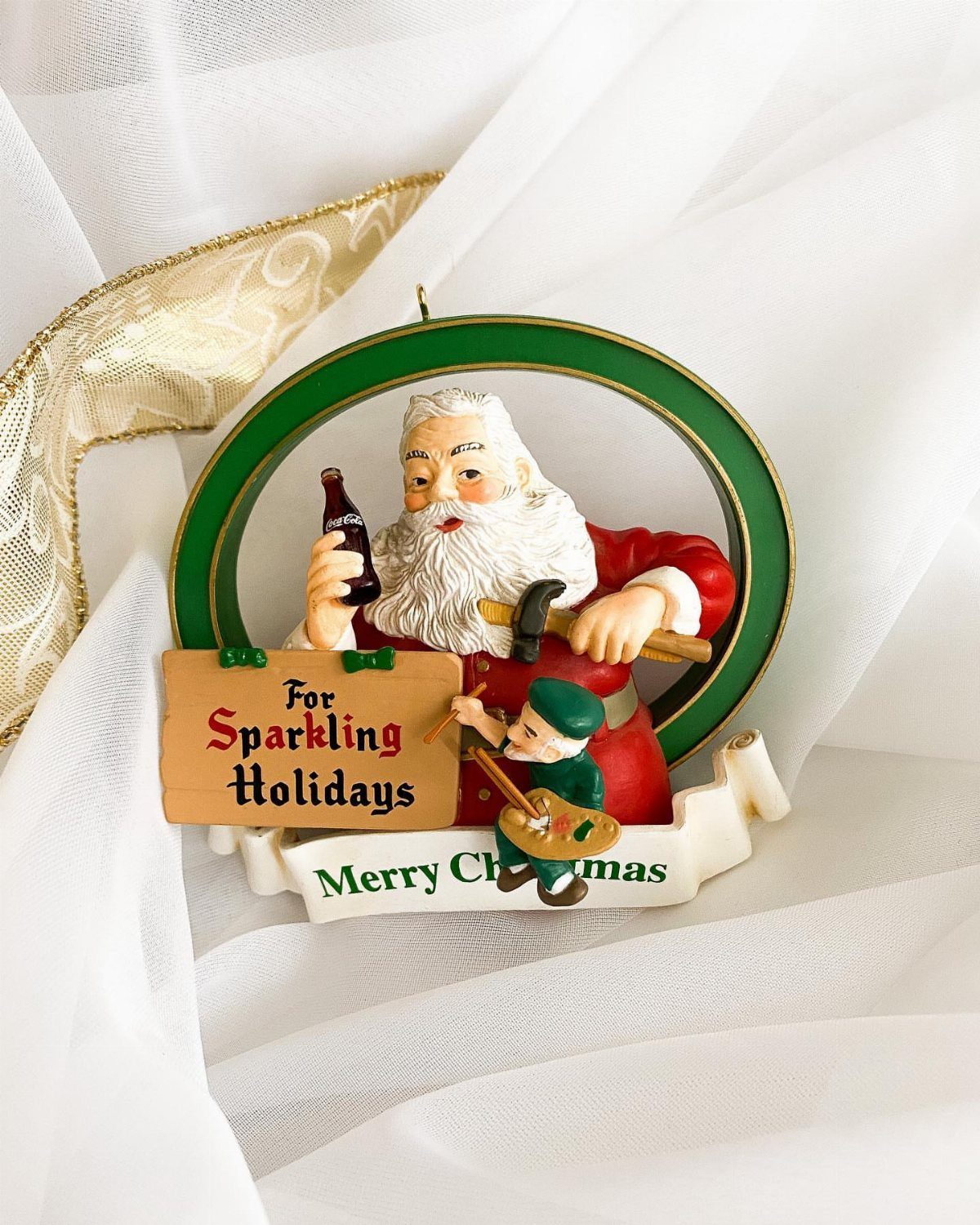 Santa Claus ornament holding a Coca-Cola bottle with a small elf playing banjo.