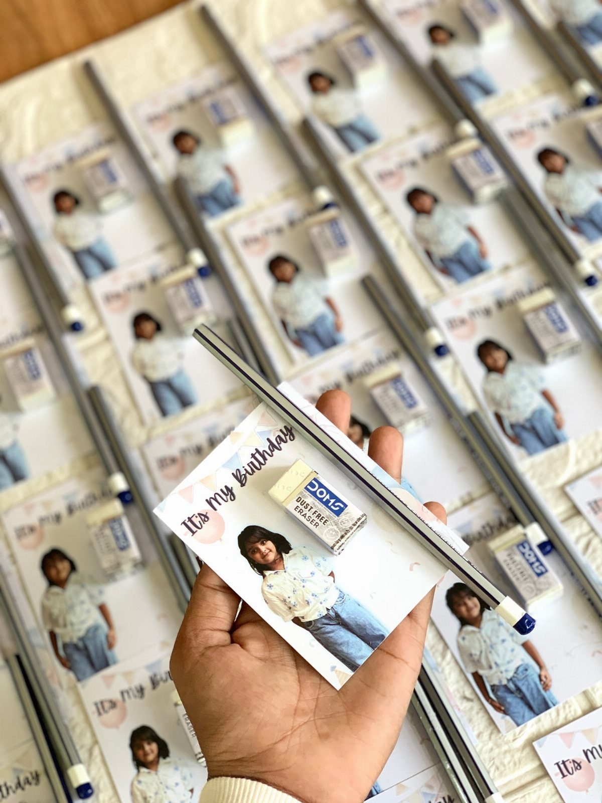 Personalized birthday stationery sets with photos, erasers, and pens on a white surface.