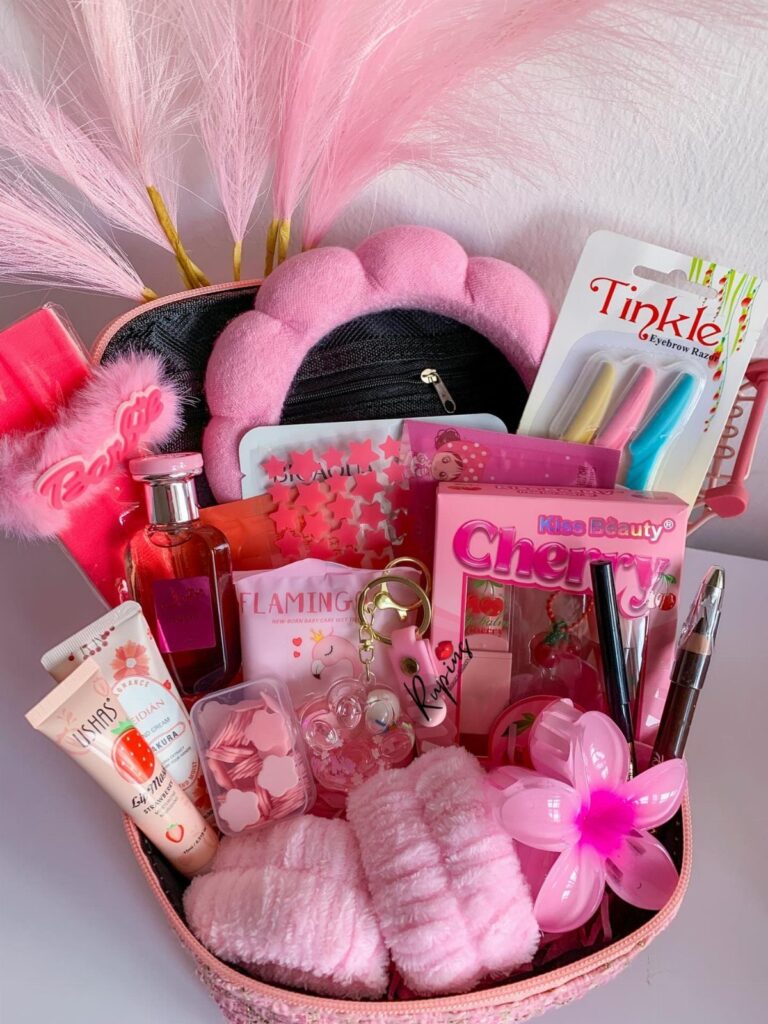Pink gift basket filled with beauty products, skincare, and a plush headband.