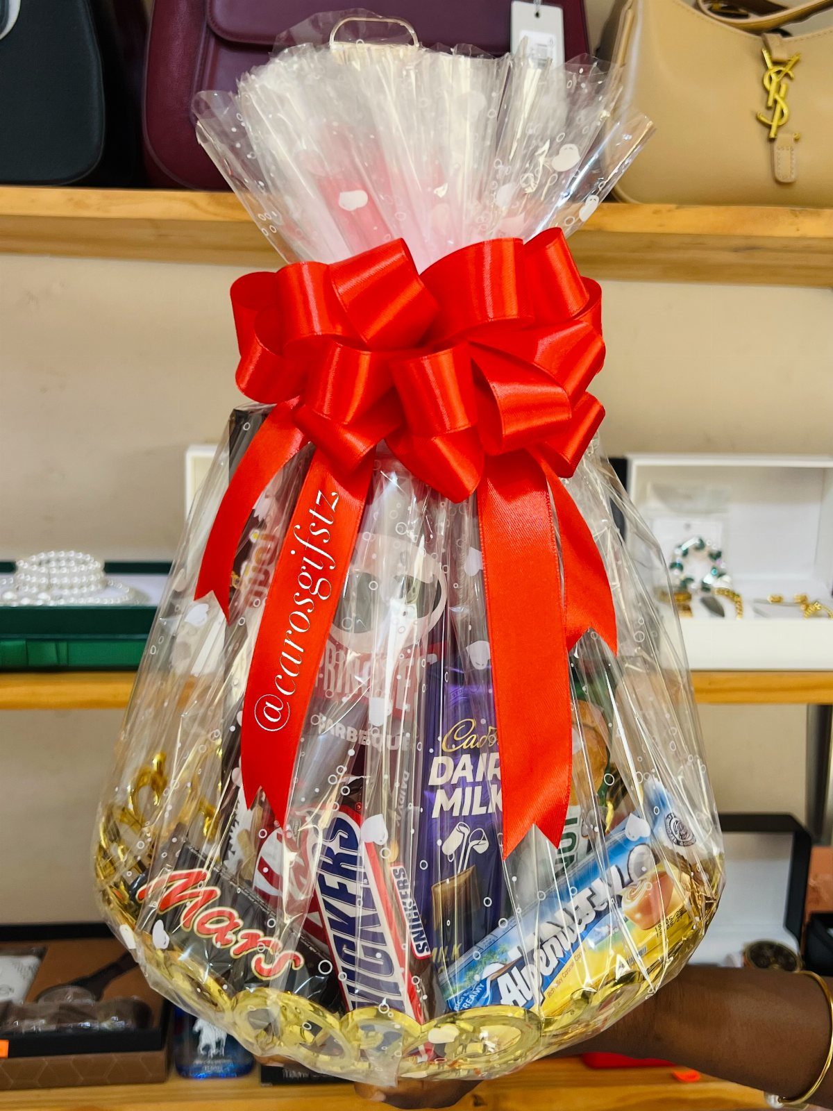 Chocolate gift basket wrapped in clear cellophane with a large red ribbon bow.