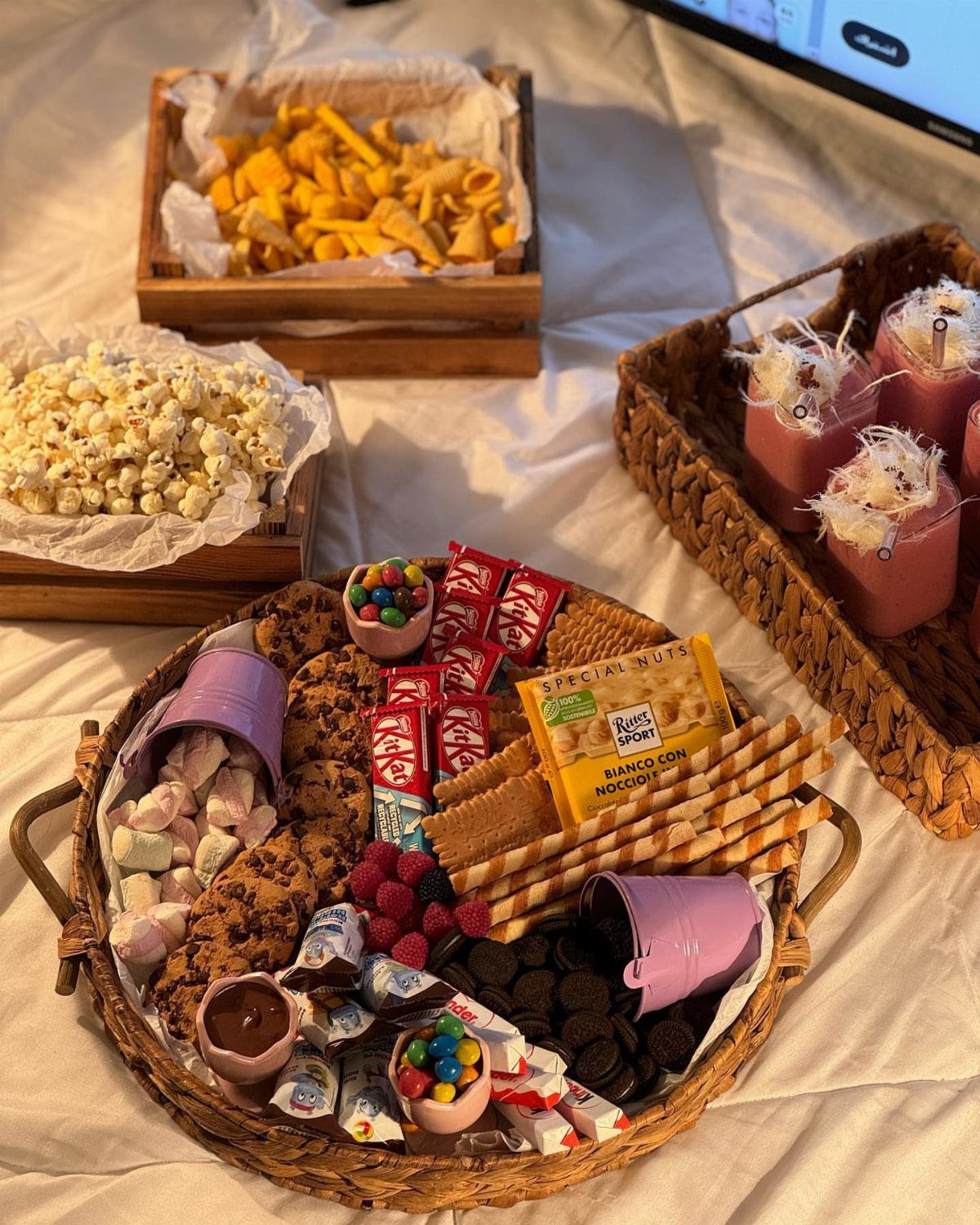 Wicker tray of sweets and snacks with popcorn and chips on a white cloth