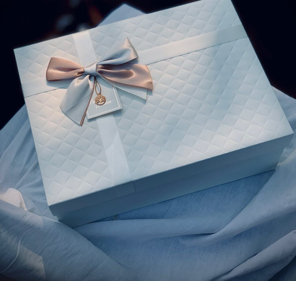Light blue quilted gift box with a satin bow and small white tag.