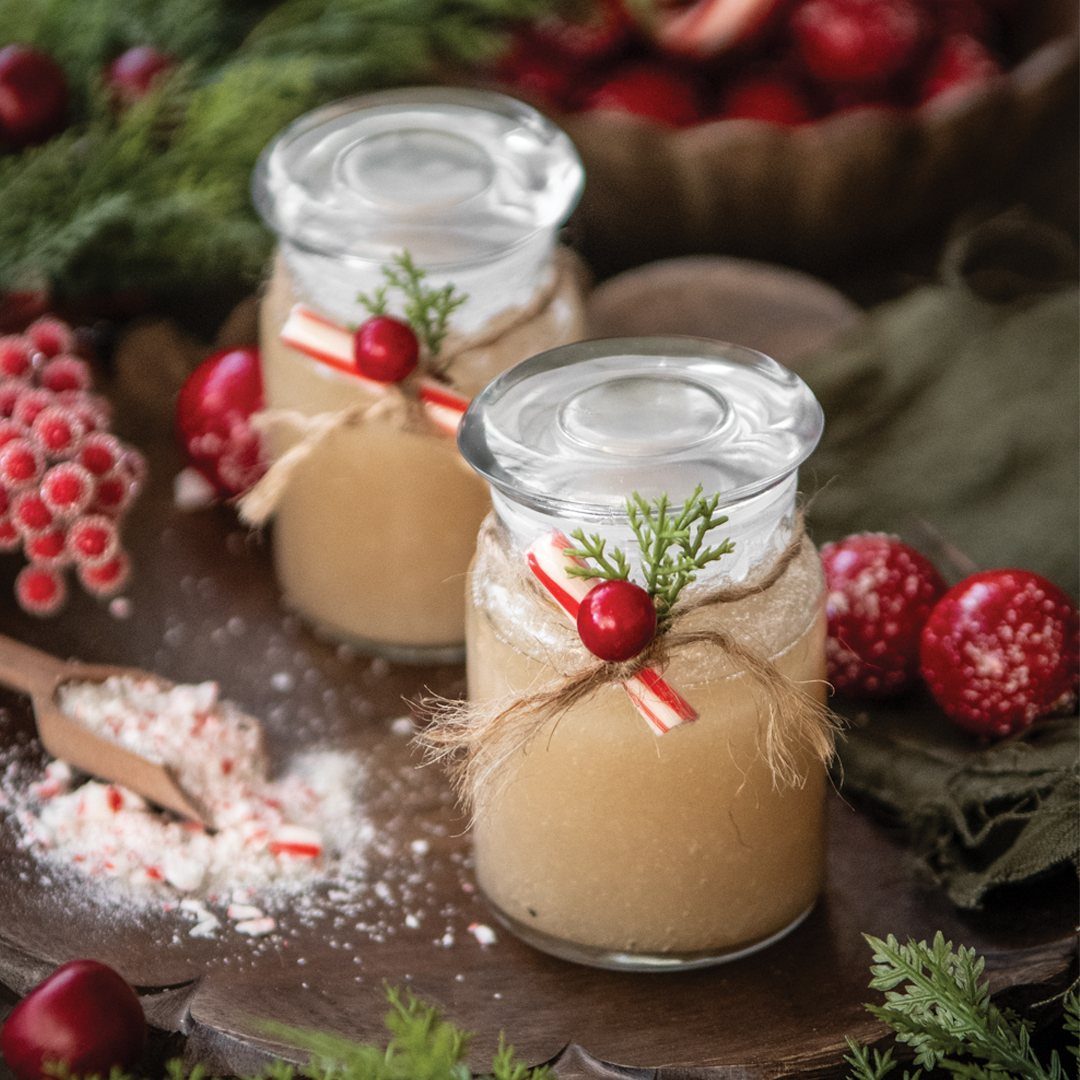Two glass jars of homemade sugar scrub decorated with twine and peppermint candies.