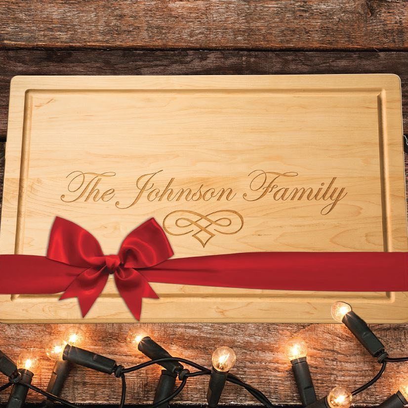 Engraved wooden cutting board with a red ribbon bow on rustic wood background.