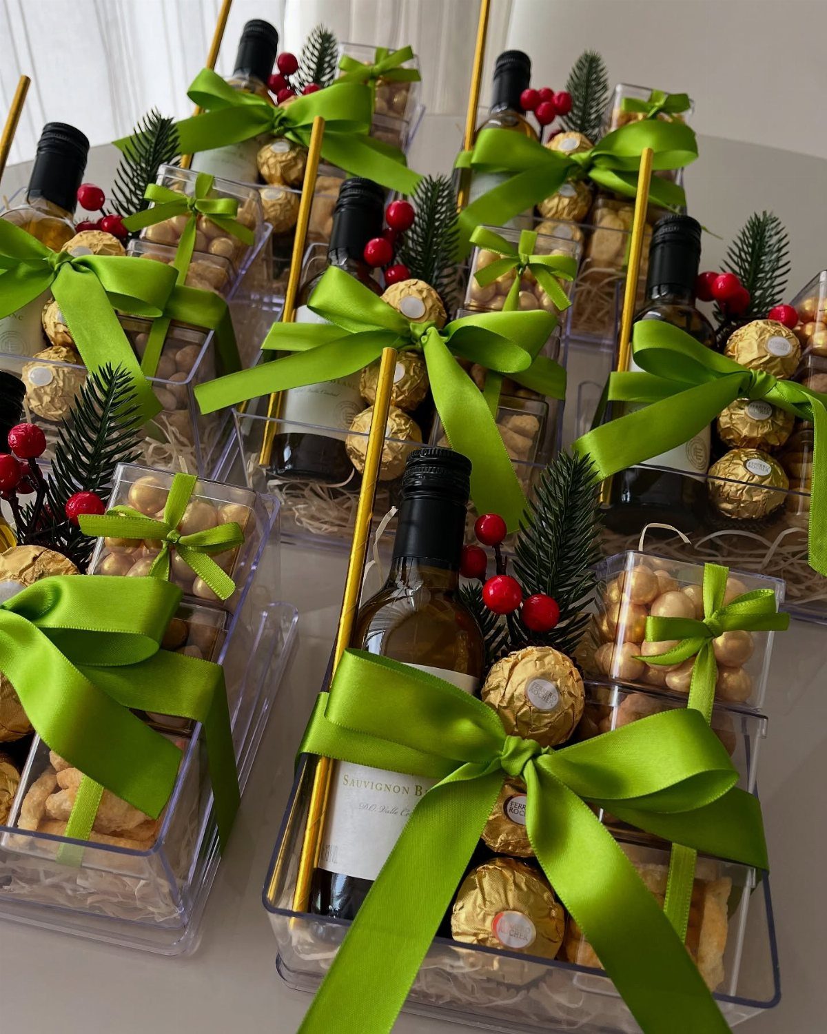 Wine gift baskets with green ribbons, chocolates, and nuts in clear packaging.