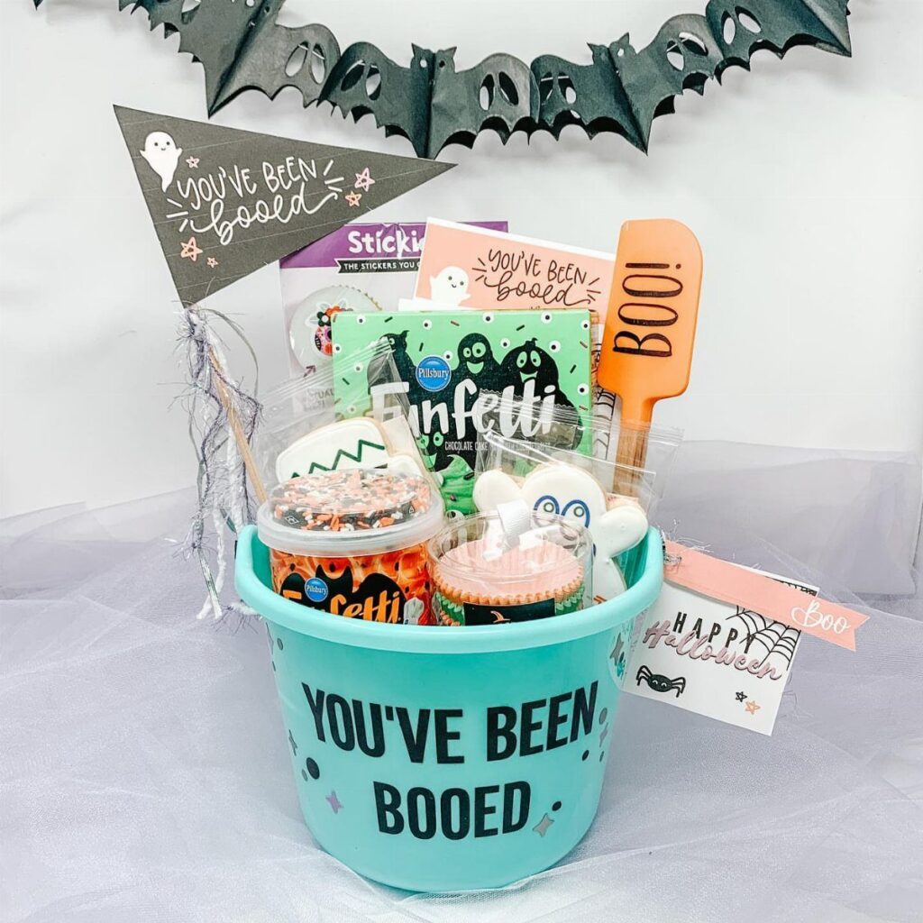 Light blue bucket filled with Halloween treats and a You've Been Booed sign.