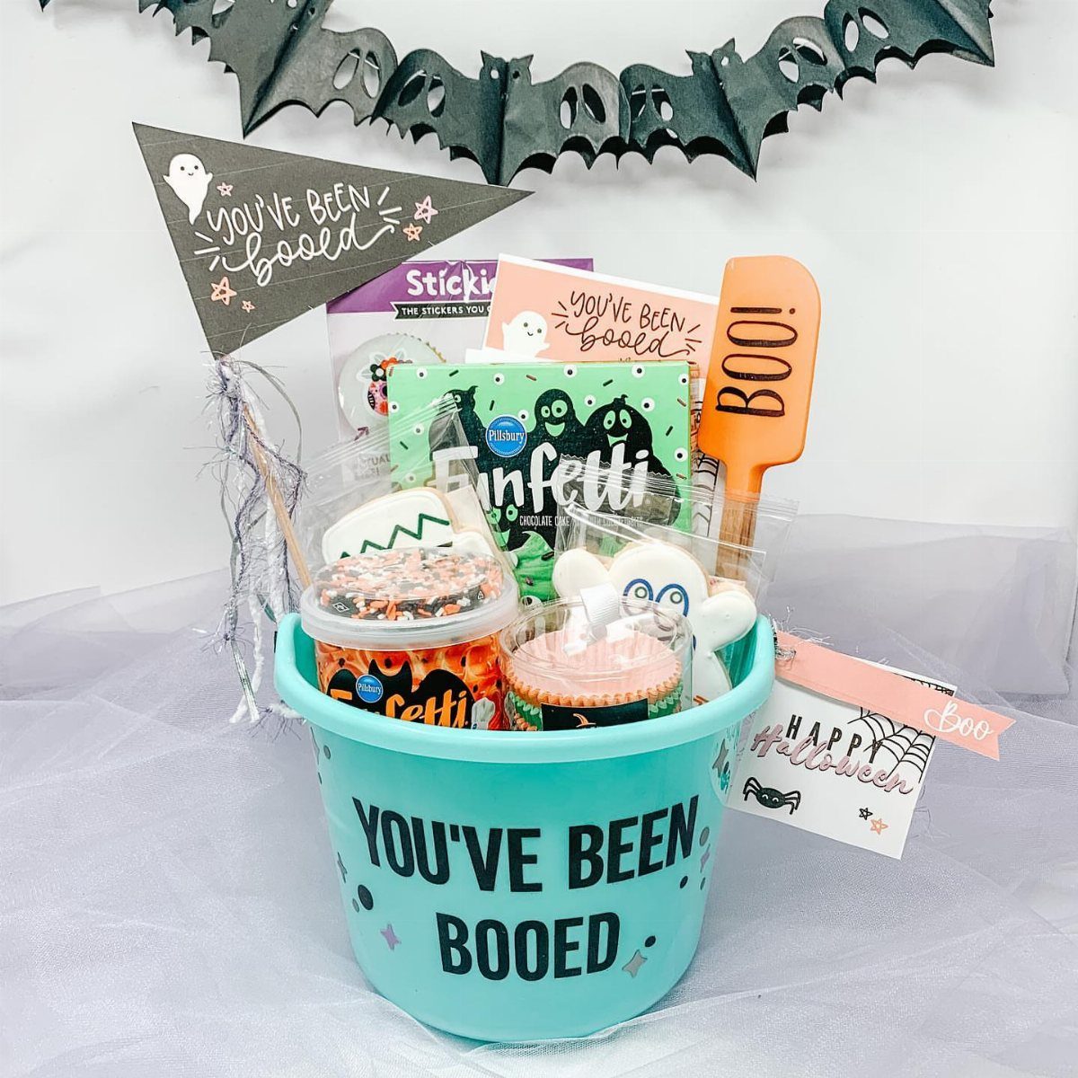 Light blue bucket filled with Halloween treats and a You've Been Booed sign.