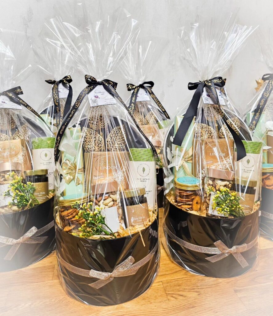 Round black gift baskets wrapped in cellophane with gourmet treats and black ribbons.