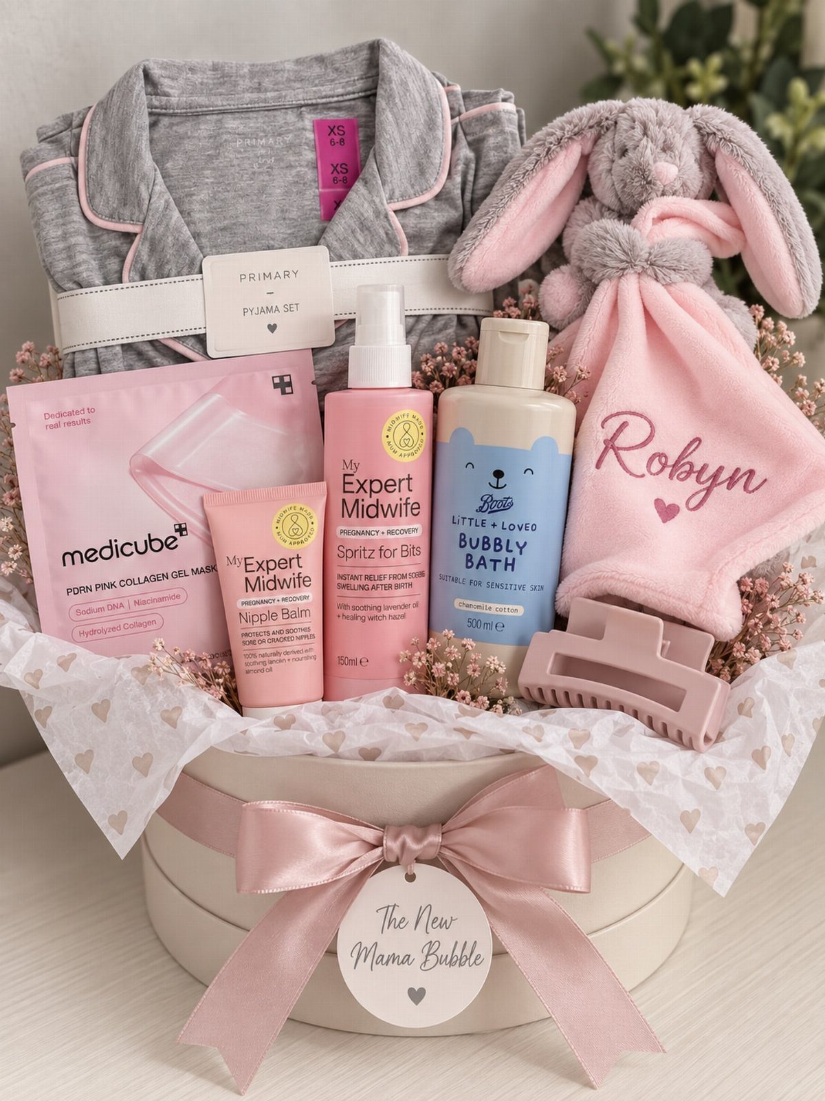 Gift basket with grey pajamas, pink bunny plush, and skincare for a new mother.