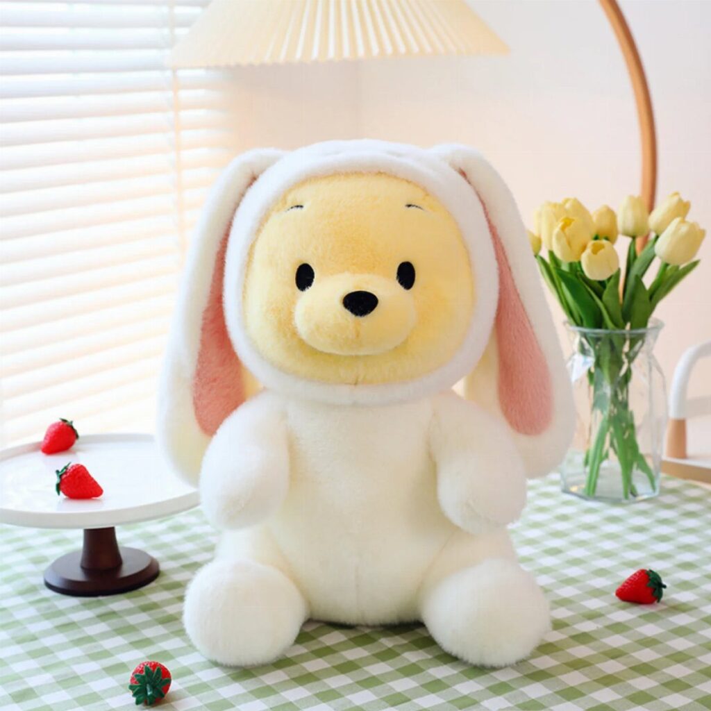 Plush yellow character in a white bunny costume sitting on a checkered tablecloth.