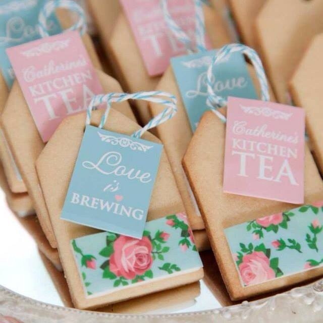Tea bag-shaped cookies with floral decorations and small paper tags on a platter.