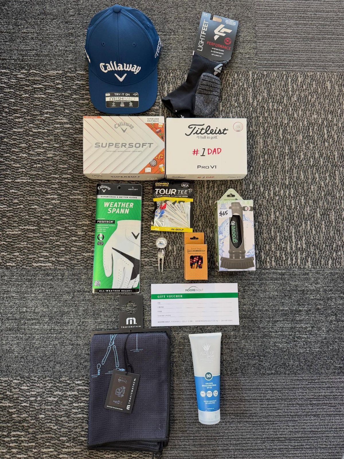 Golf accessories including a blue hat, golf balls, and gear arranged on grey carpet.